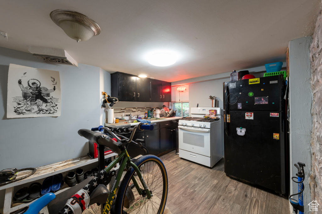 Kitchen with white gas range, freestanding refrigerator, and light wood-type flooring