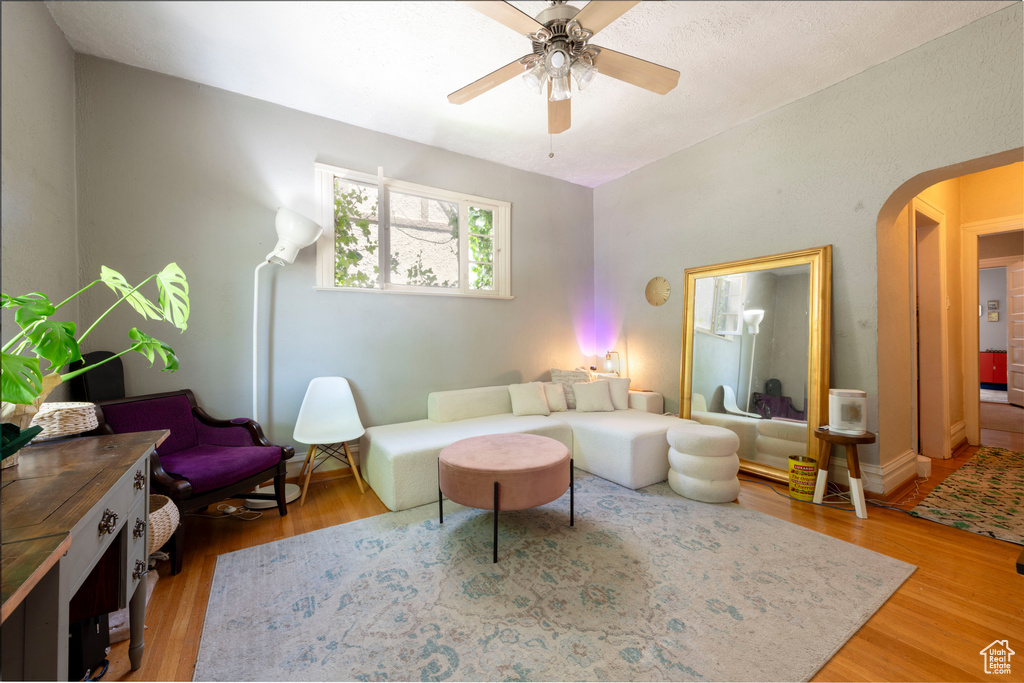 Living room featuring arched walkways, light wood-type flooring, and ceiling fan