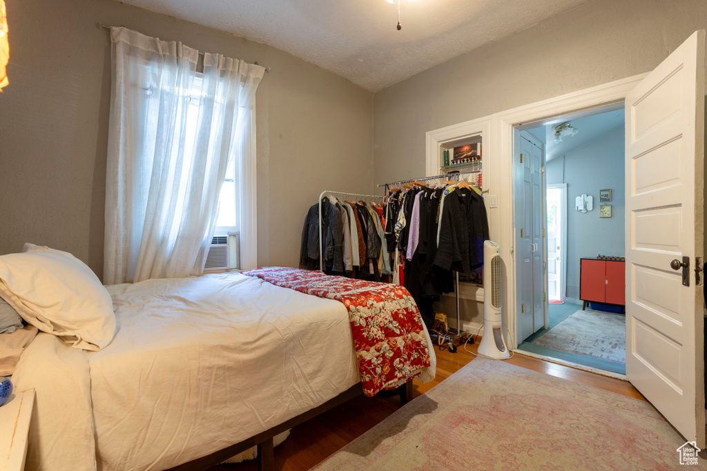 Bedroom featuring wood finished floors, vaulted ceiling, and cooling unit