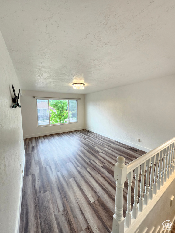 Unfurnished living room with wood finished floors, baseboards, and a textured ceiling