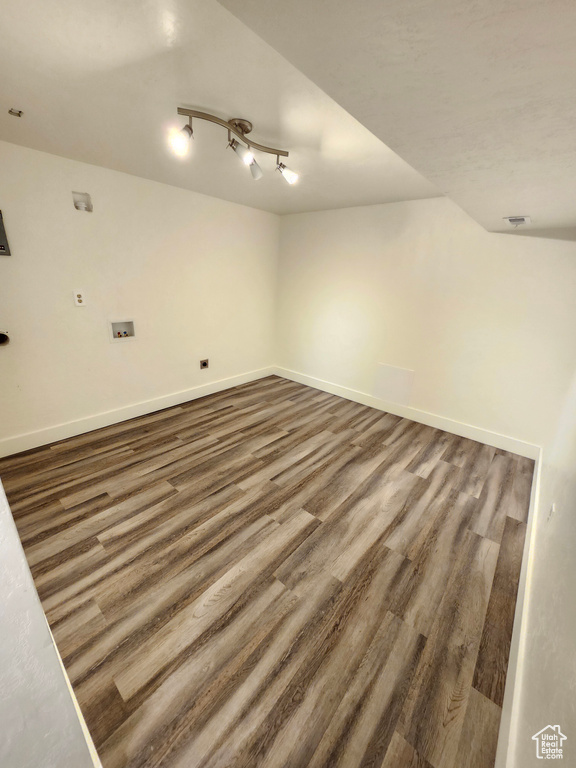 Unfurnished room with wood finished floors, baseboards, and rail lighting