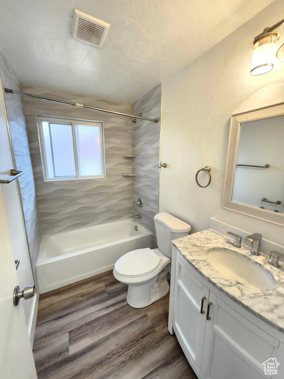 Bathroom featuring vanity, bathtub / shower combination, wood finished floors, and toilet