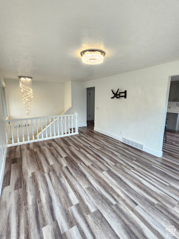 Empty room featuring wood finished floors, baseboards, and a chandelier