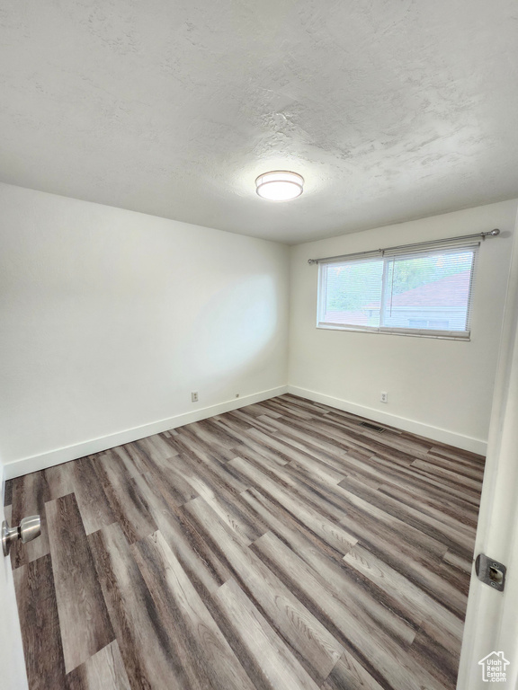 Spare room with wood finished floors, baseboards, and a textured ceiling