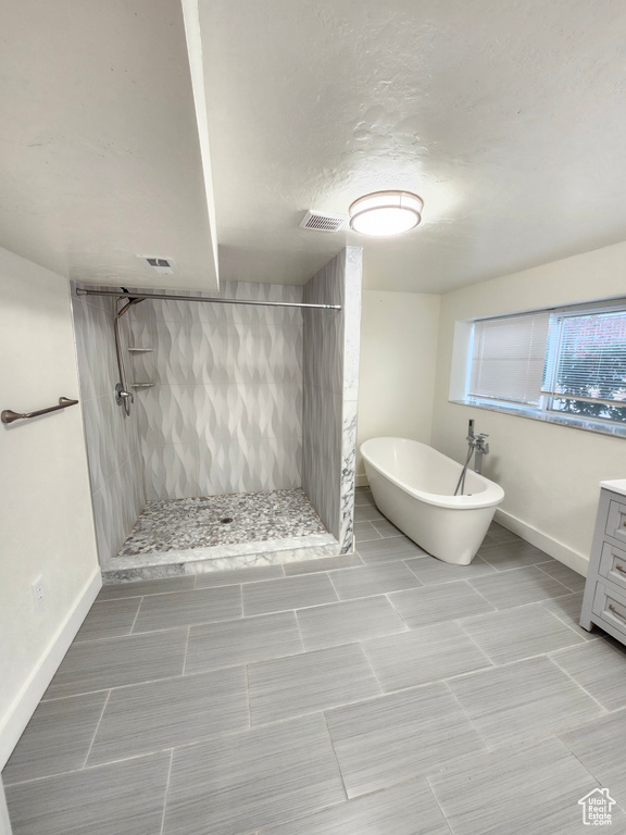 Full bathroom with tiled shower, a soaking tub, baseboards, and vanity