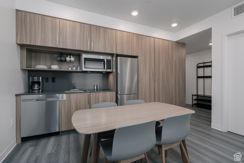 Kitchen featuring stainless steel appliances, dark wood-type flooring, baseboards, a sink, and modern cabinets