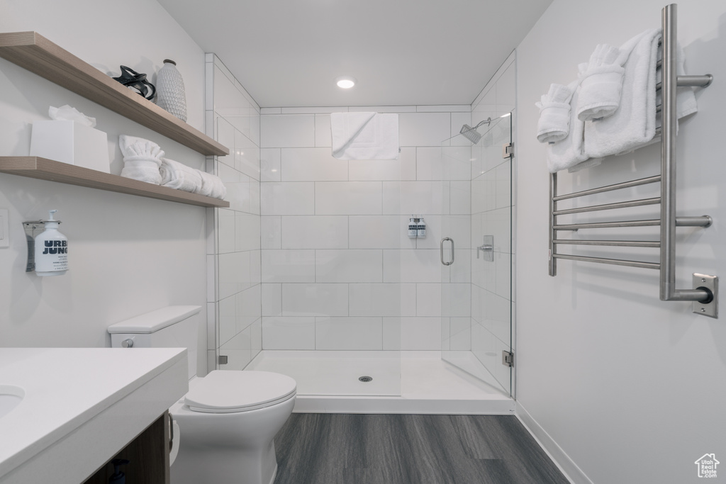 Bathroom with radiator, toilet, a stall shower, wood finished floors, and vanity