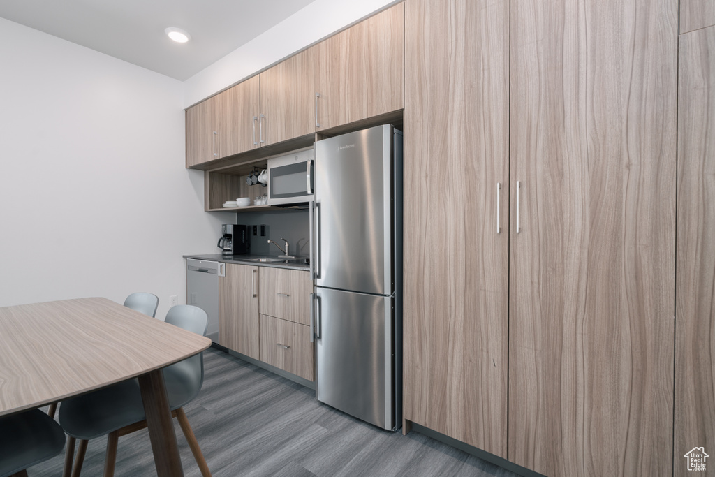 Kitchen featuring appliances with stainless steel finishes, wood finished floors, a sink, modern cabinets, and open shelves