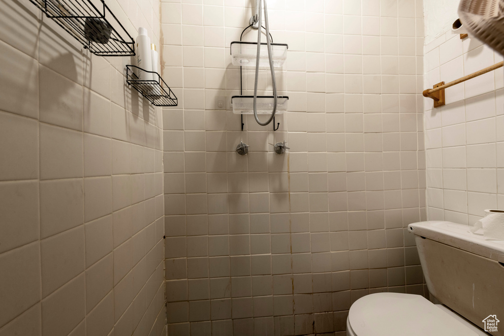 Bathroom with toilet and tile walls