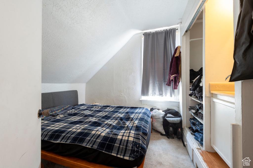 Carpeted bedroom with lofted ceiling and a textured ceiling