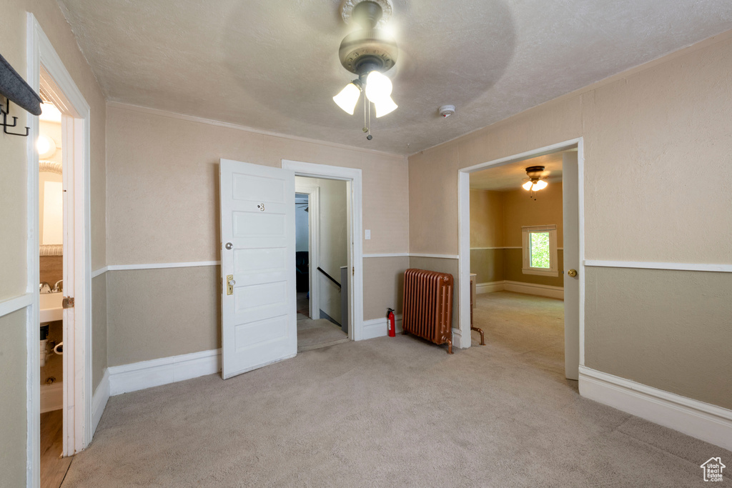 Unfurnished bedroom with radiator, carpet flooring, baseboards, and a ceiling fan