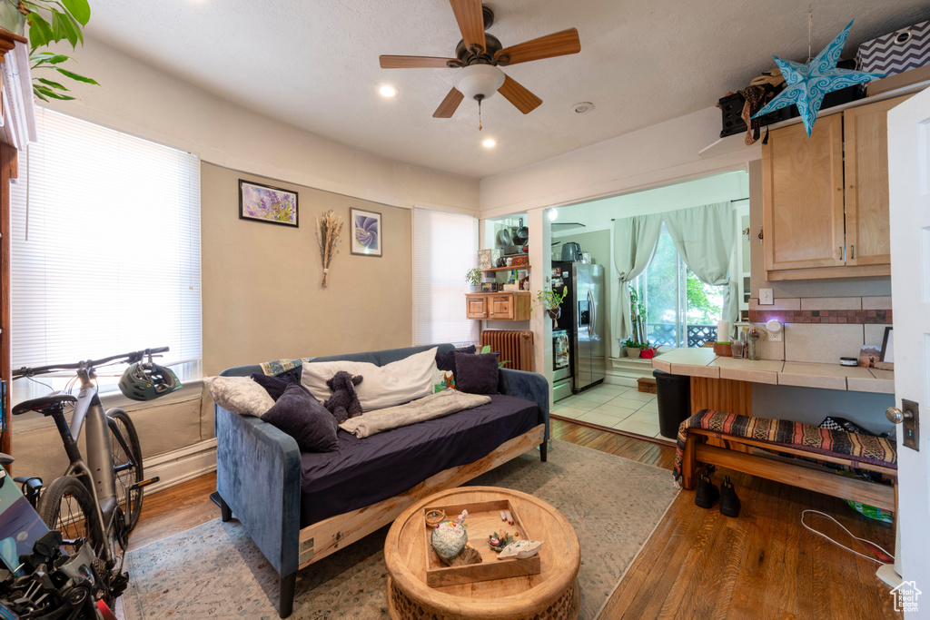 Living area featuring ceiling fan, light wood-type flooring, radiator heating unit, and recessed lighting