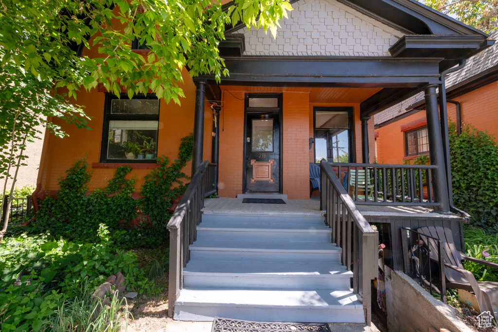 View of exterior entry with brick siding and covered porch