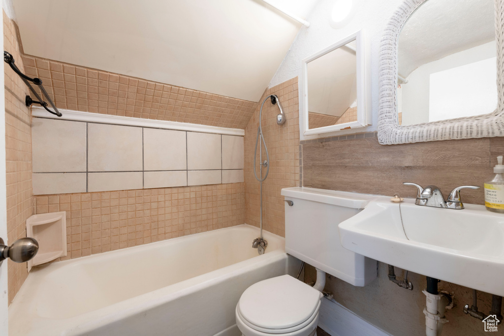 Full bathroom featuring lofted ceiling, toilet, bathing tub / shower combination, and tile walls