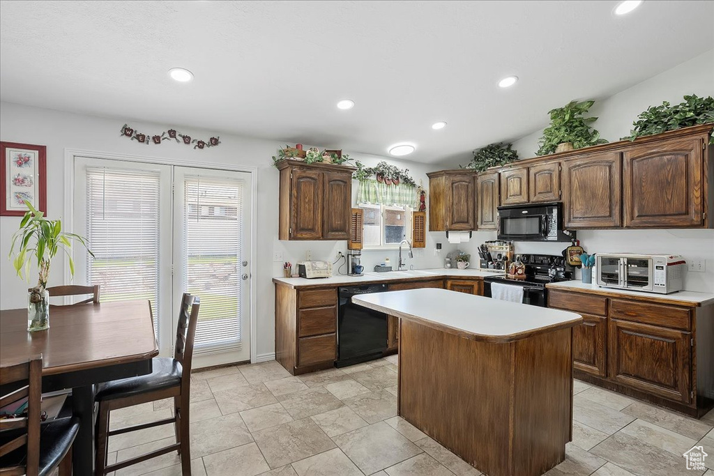 Kitchen with black appliances, a sink, light countertops, a kitchen island, and recessed lighting