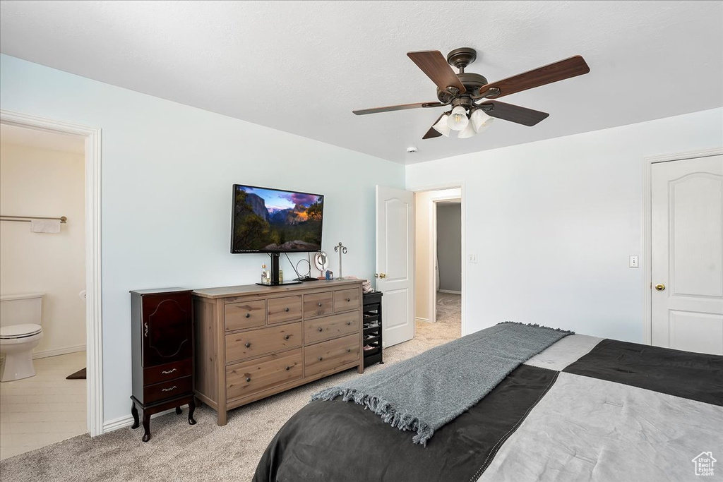 Bedroom featuring light colored carpet, baseboards, ensuite bathroom, and ceiling fan