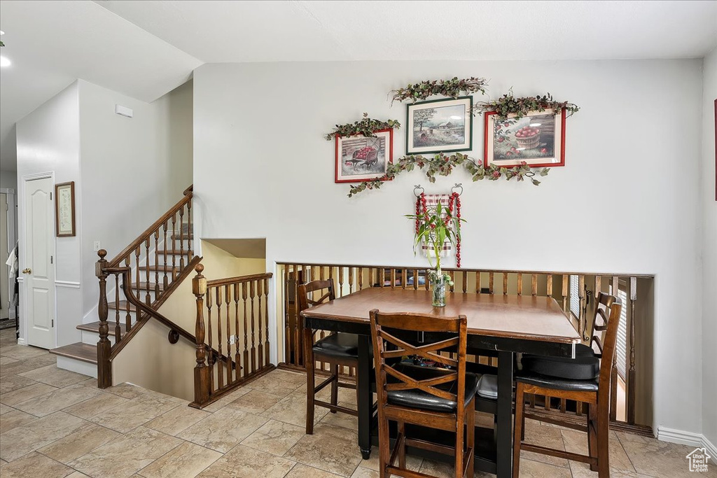 Dining room with lofted ceiling, baseboards, and stairway