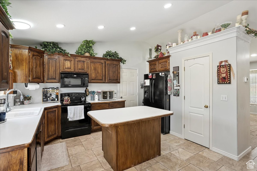 Kitchen featuring black appliances, a sink, light countertops, a center island, and recessed lighting