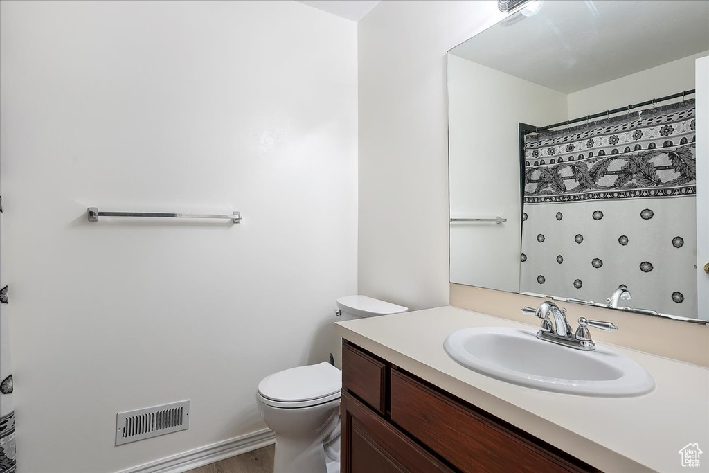 Full bath with toilet, vanity, and wood finished floors