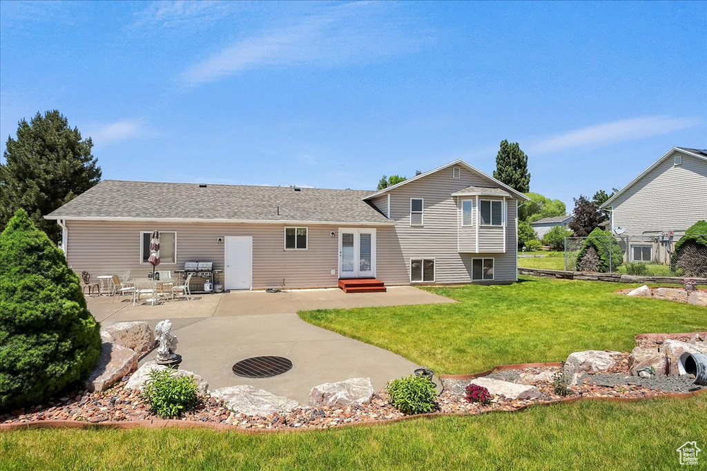 Back of property featuring french doors, a patio area, a yard, entry steps, and roof with shingles