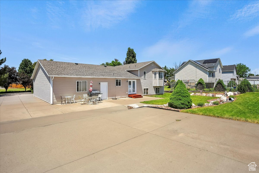 Back of property with a patio area, roof with shingles, entry steps, and a lawn
