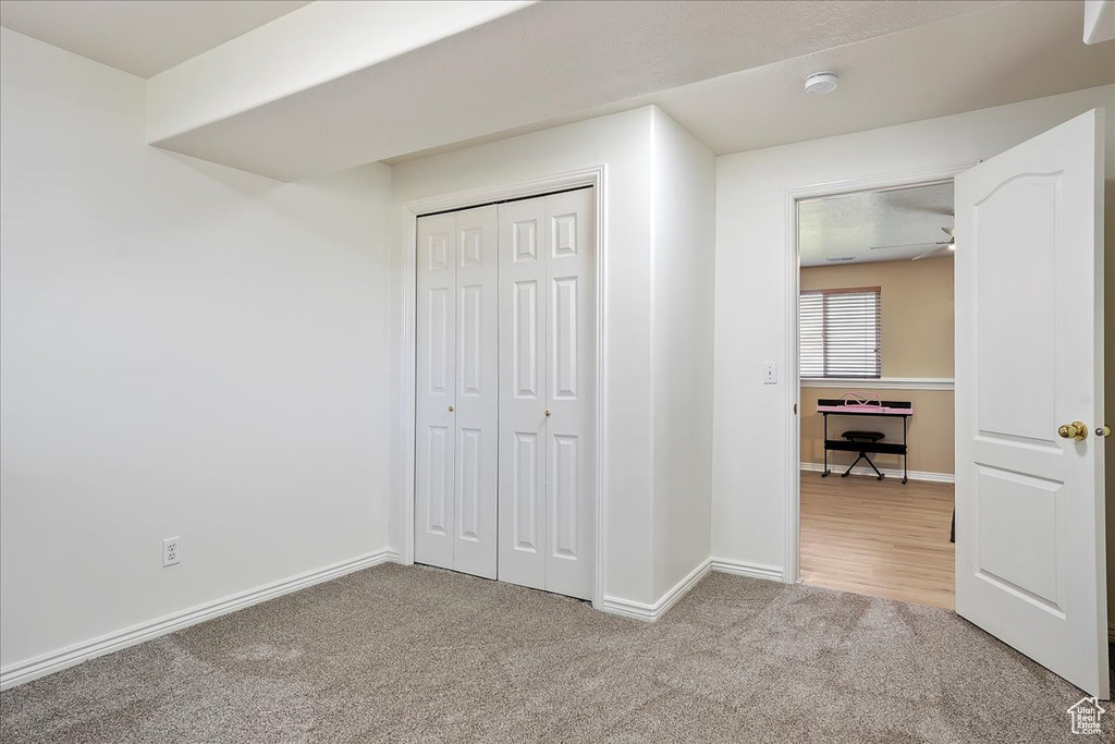 Unfurnished bedroom with light colored carpet, baseboards, and a closet