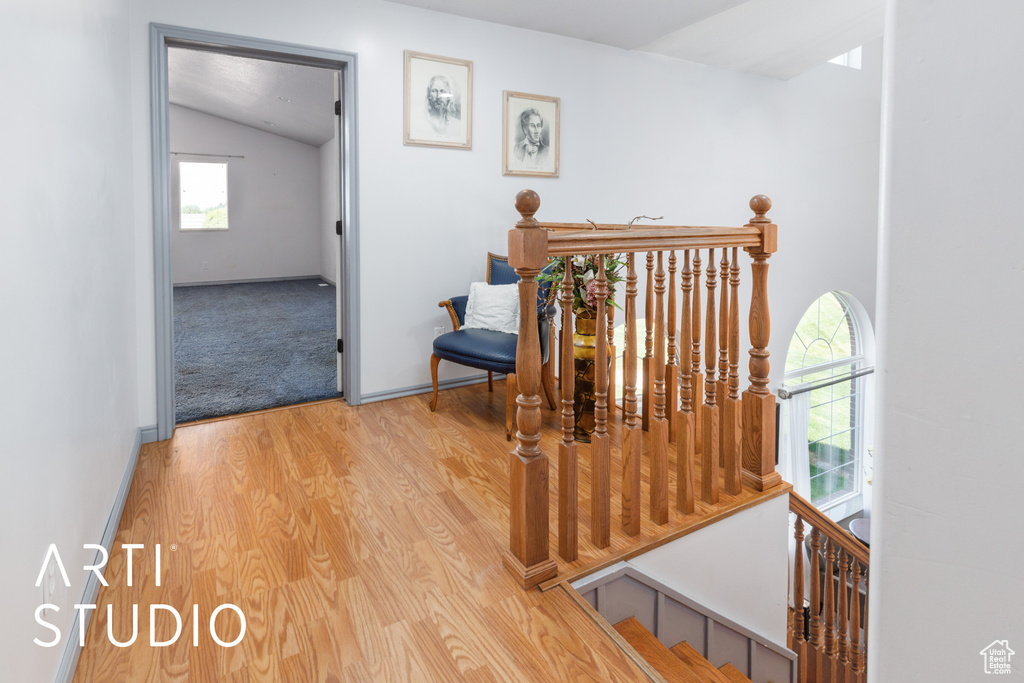 Corridor featuring an upstairs landing, lofted ceiling, wood finished floors, and baseboards