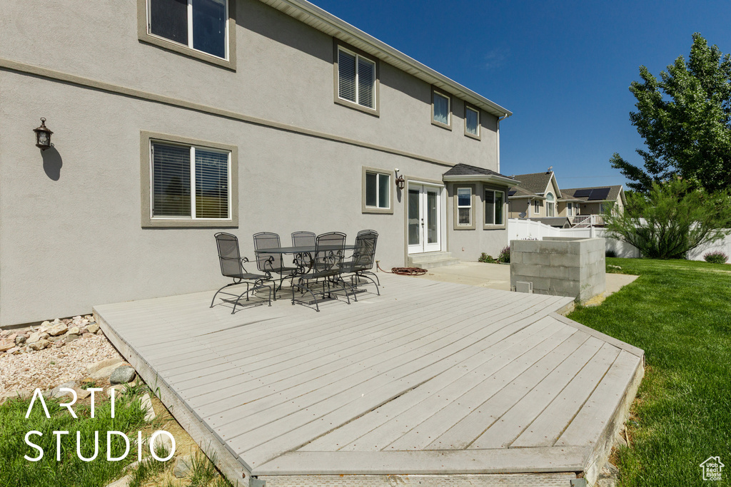 Wooden terrace with french doors, outdoor dining space, and a lawn