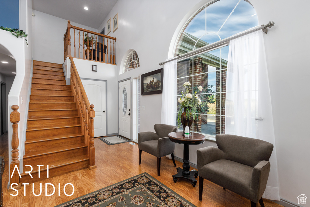 Entrance foyer featuring healthy amount of natural light, stairway, wood finished floors, a towering ceiling, and baseboards