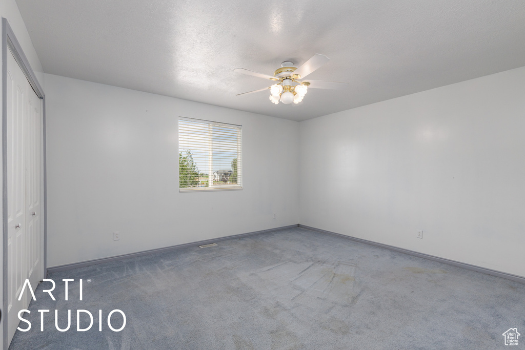 Carpeted spare room featuring ceiling fan and baseboards