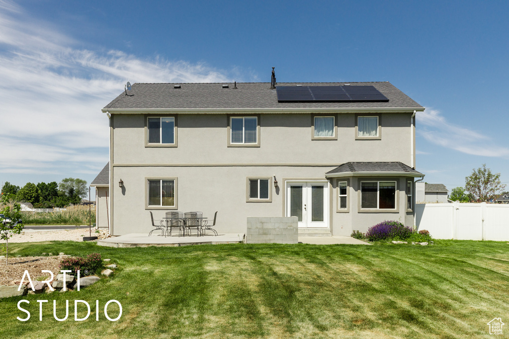 Rear view of property with french doors, a patio area, solar panels, and stucco siding