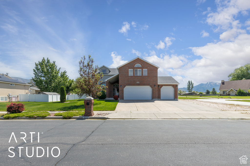 Traditional home featuring an attached garage, brick siding, driveway, and a mountain view