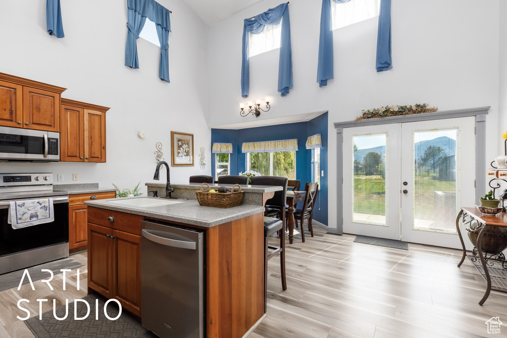 Kitchen with appliances with stainless steel finishes, a sink, high vaulted ceiling, brown cabinets, and french doors