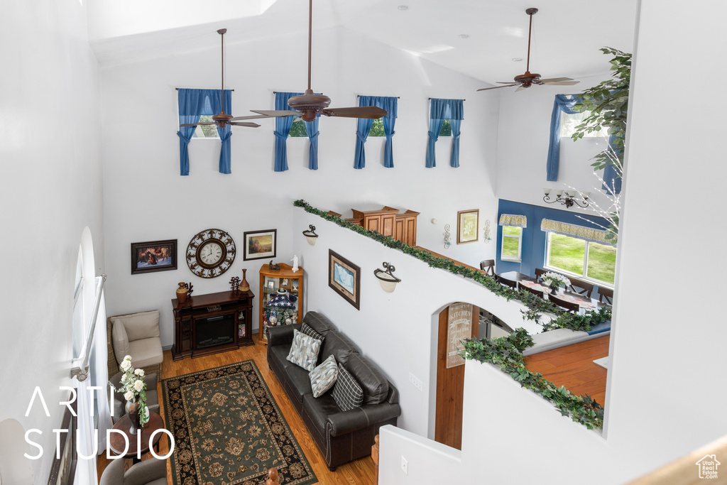 Living room with high vaulted ceiling, a ceiling fan, and wood finished floors