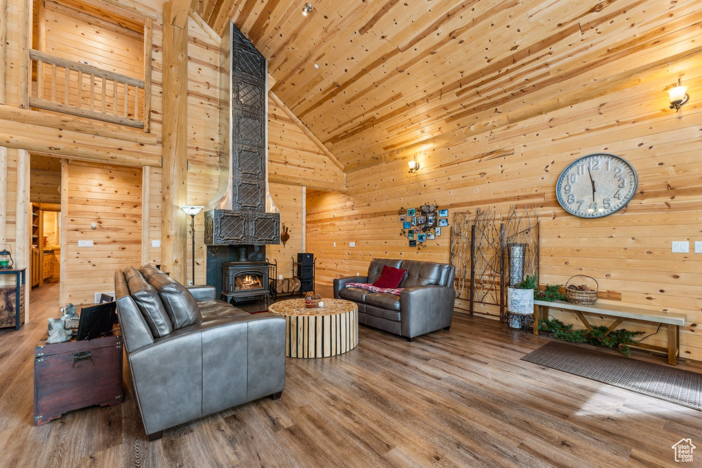 Living room featuring high vaulted ceiling, a wood stove, wood walls, wood ceiling, and wood finished floors
