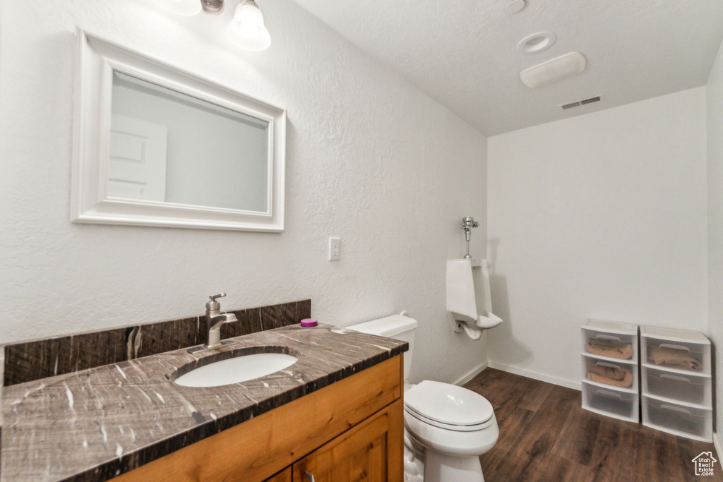 Bathroom featuring wood finished floors, toilet, vanity, and baseboards