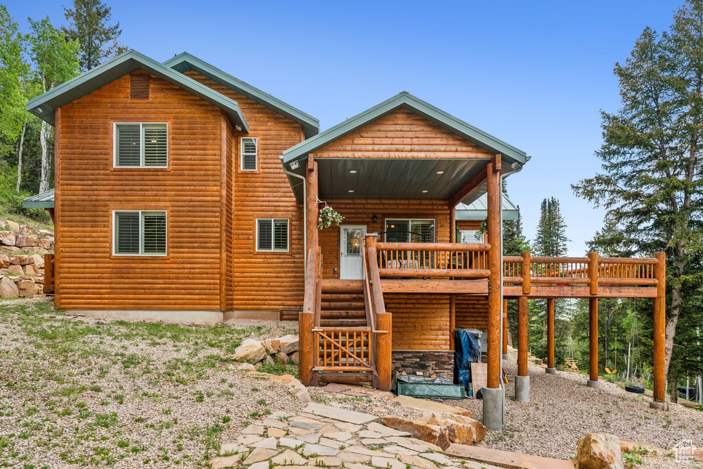 Rear view of property with log veneer siding, a wooden deck, and stairway