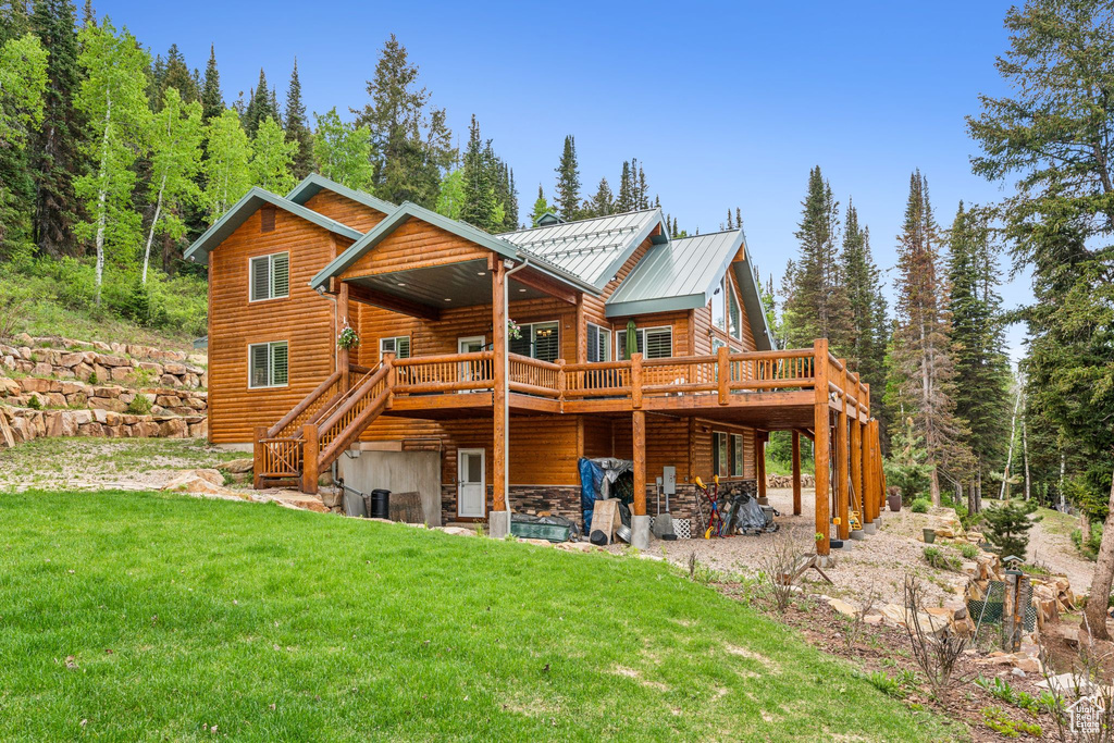 Back of property featuring a standing seam roof, a lawn, a deck, metal roof, and stairway