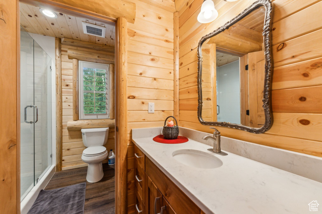 Bathroom with wood finished floors, toilet, vanity, a shower stall, and recessed lighting