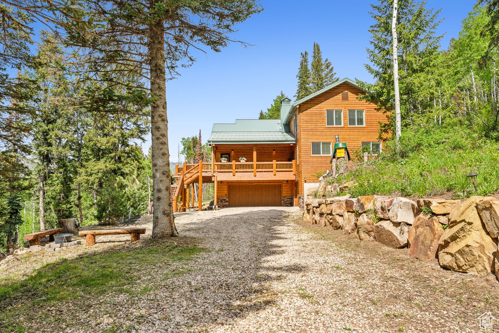 View of front of property featuring gravel driveway, a garage, metal roof, and stairway