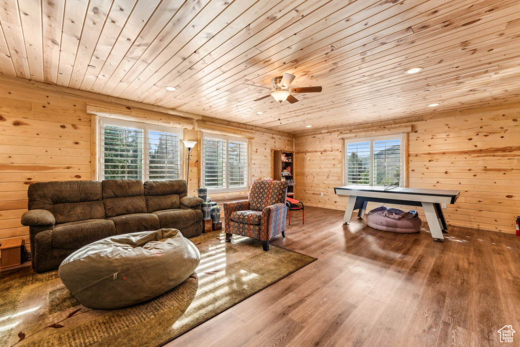 Living area featuring wooden ceiling, healthy amount of natural light, wood finished floors, wooden walls, and ceiling fan
