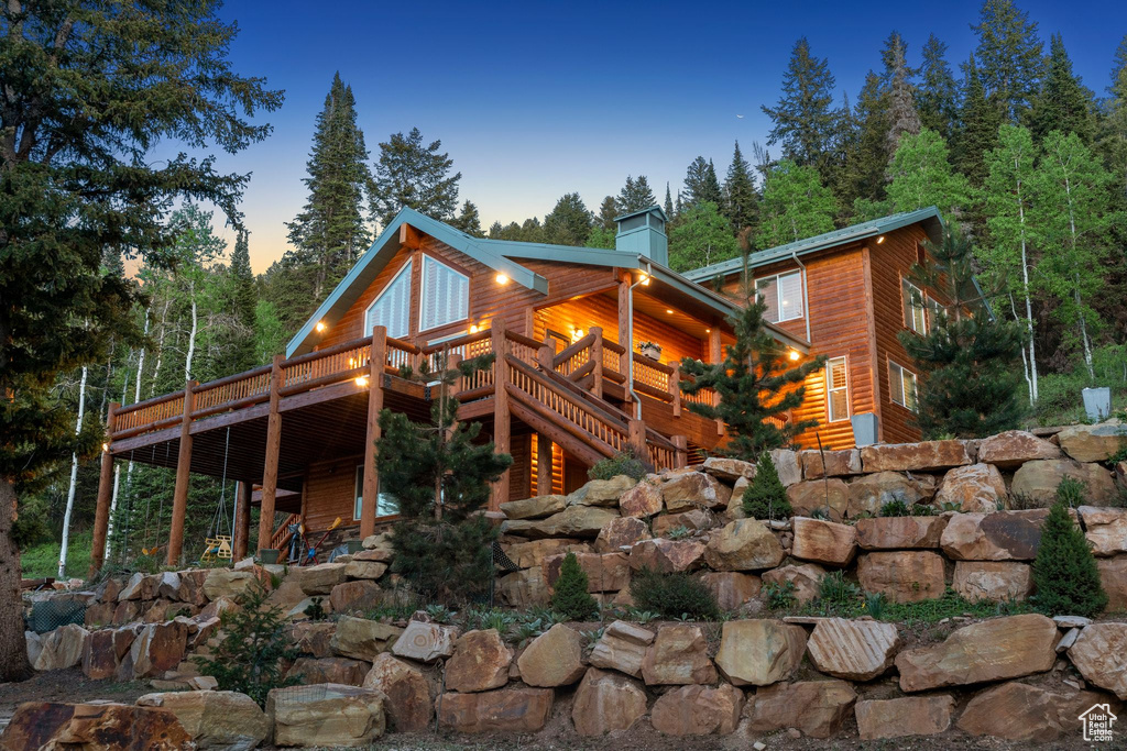 Rear view of house featuring a wooden deck, a chimney, and log veneer siding