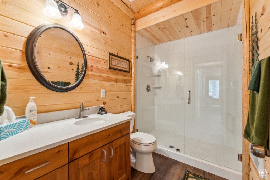 Full bathroom with vanity, a shower stall, toilet, wood walls, and wood finished floors