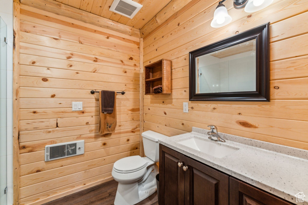 Bathroom with wooden walls, toilet, vanity, wooden ceiling, and wood finished floors