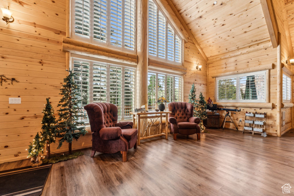 Sitting room with high vaulted ceiling, wooden walls, wood finished floors, and wood ceiling