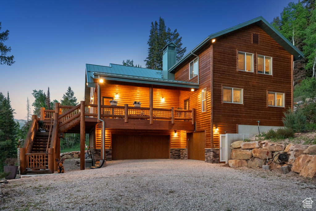 Rustic home featuring stairs, a chimney, driveway, a garage, and metal roof