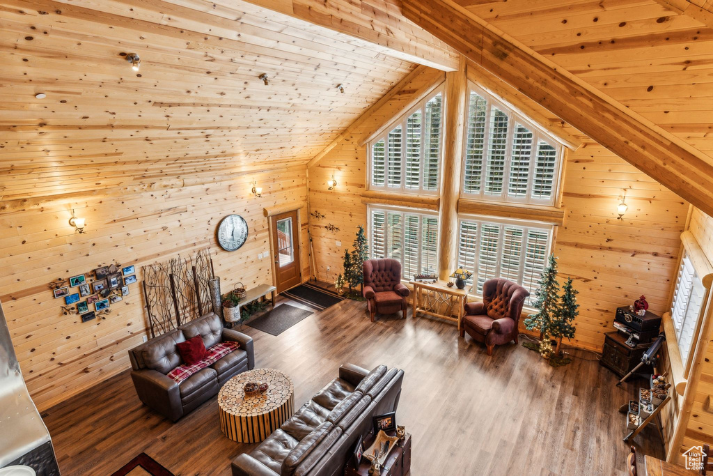 Living room with wooden walls, wood finished floors, healthy amount of natural light, wood ceiling, and vaulted ceiling