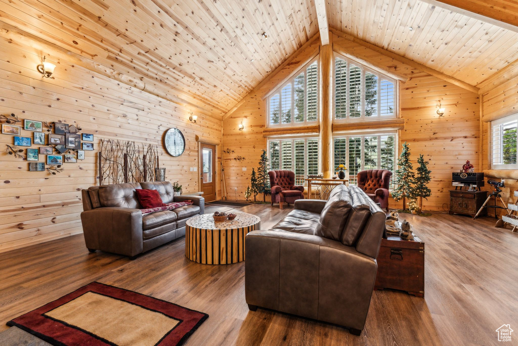 Living area featuring wooden walls, high vaulted ceiling, wood finished floors, and wooden ceiling with exposed beams