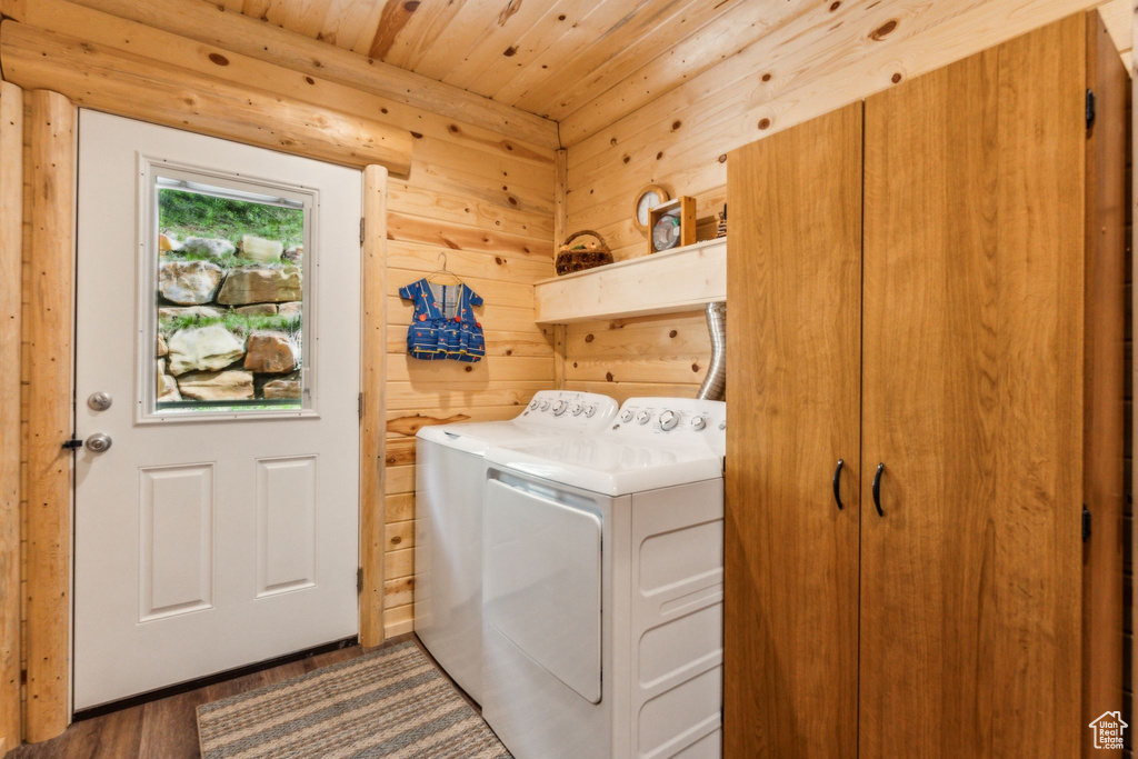 Washroom with washer and clothes dryer, wooden ceiling, wood finished floors, and wooden walls
