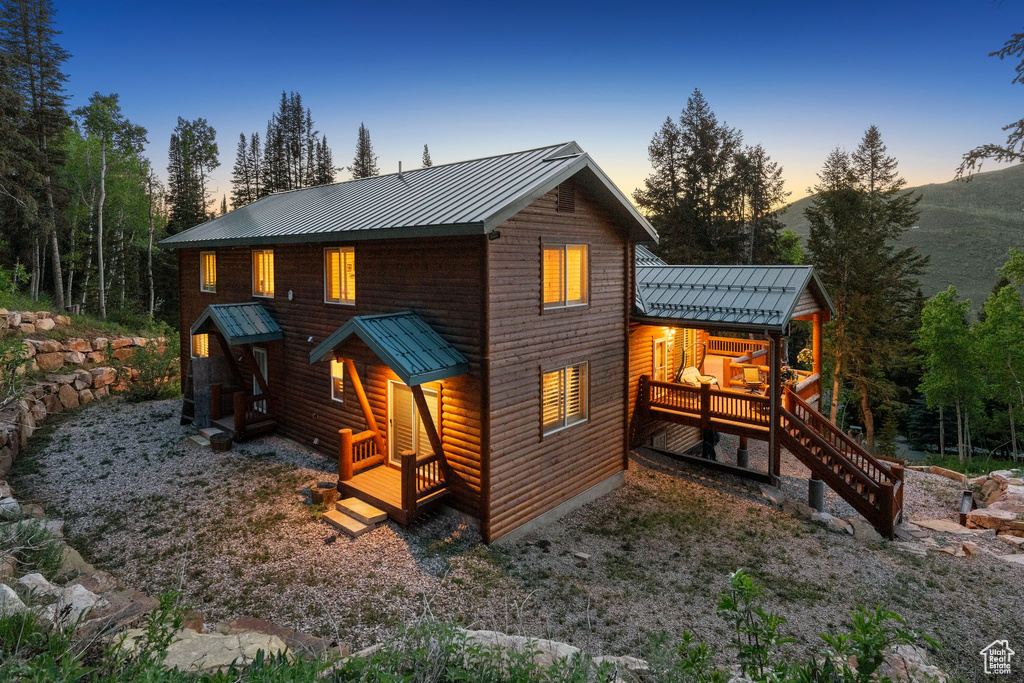 Back of house with metal roof, faux log siding, and a standing seam roof